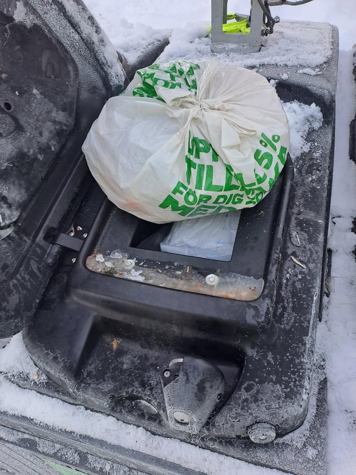 Soppåse som ligger ovanpå en öppen soptunna
